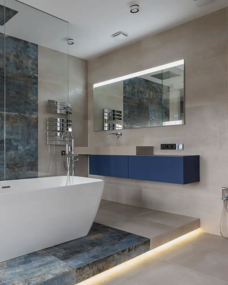 Bathroom with a freestanding tub, blue vanity and patterned tile