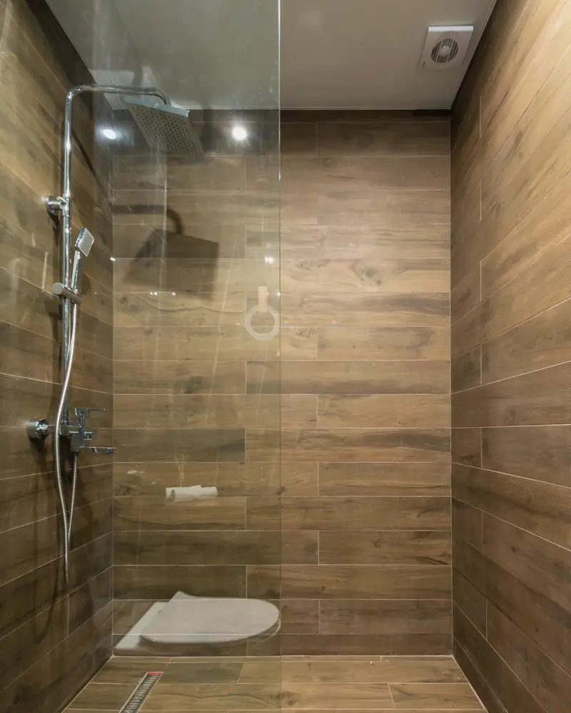 Walk-in shower with wood-look tile walls and a glass panel